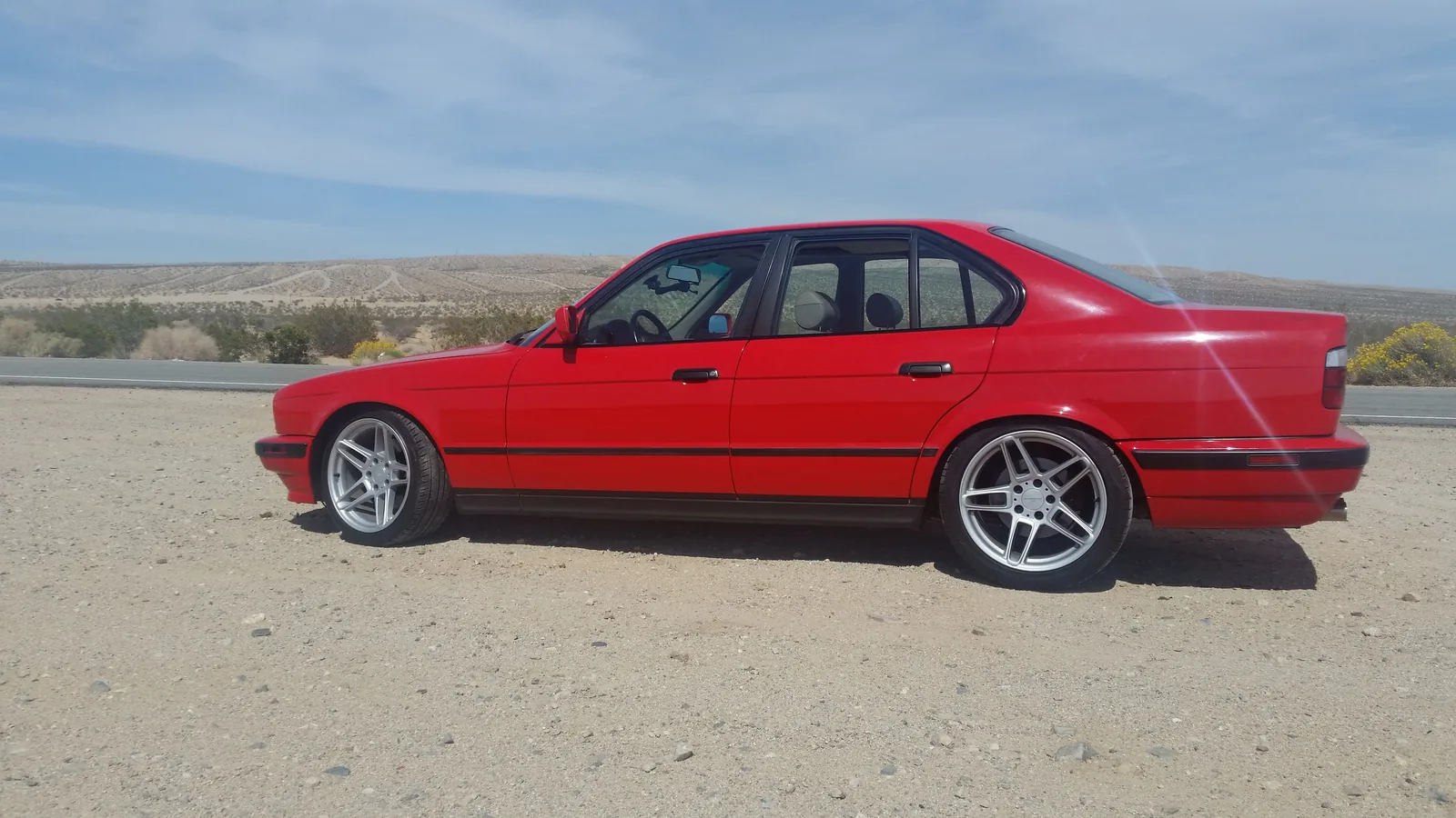 Red specialty auto shown in a neutral scenic setting.